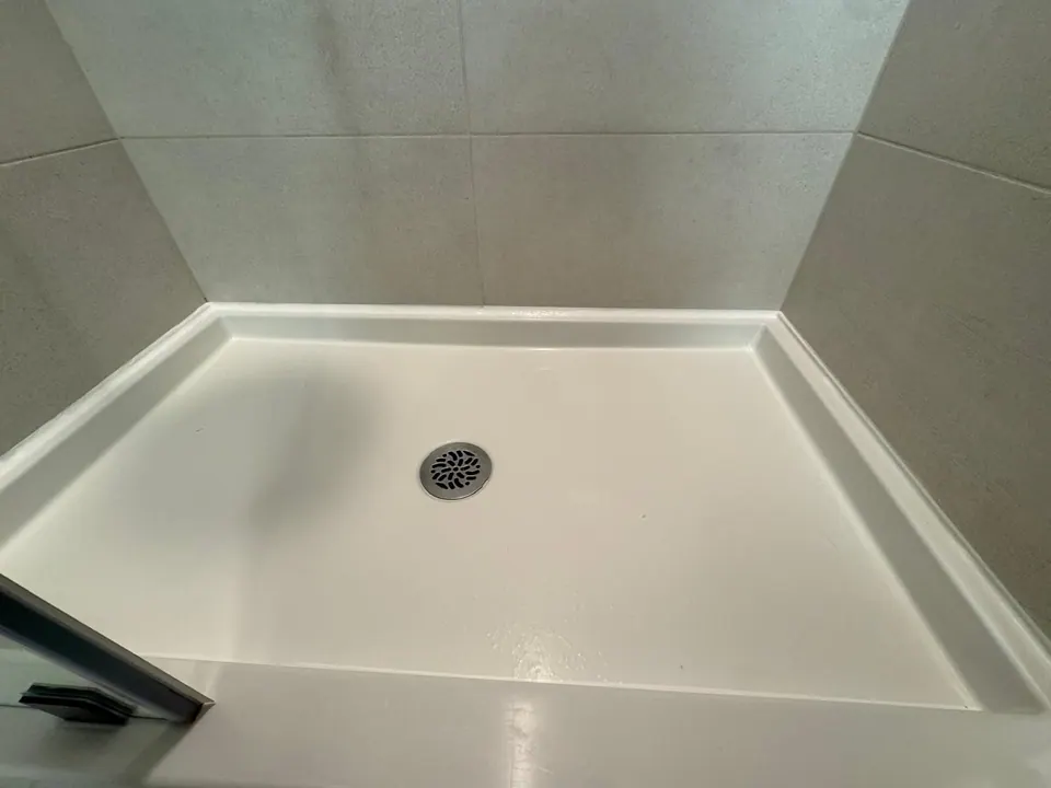 After: Shower base edge with a clean new caulk line after the tape was removed