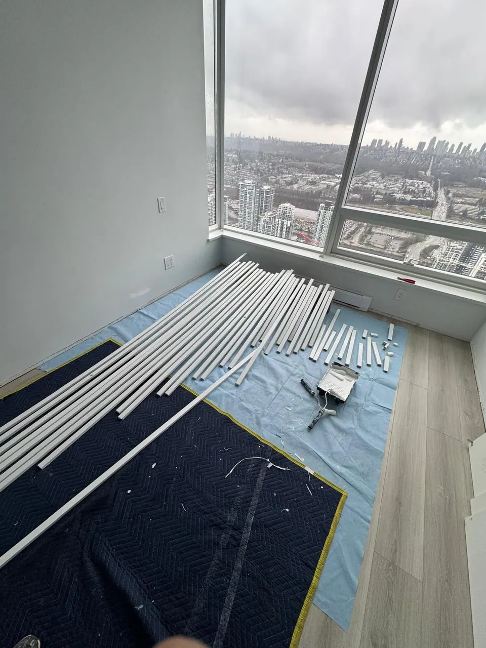 Earlier: Corner room with floor protection and baseboard lengths laid out on a high floor